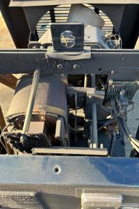 Before Steam Cleaning - Dupont Welder Services Close-up of dusty industrial machinery showing a large belt drive, a motor with windings, wiring, and a metal frame.