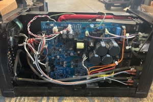 Muiltimatic before - Dupont Welder Services Internal view of a blue circuit board with capacitors and multicolored wiring inside an electronics enclosure